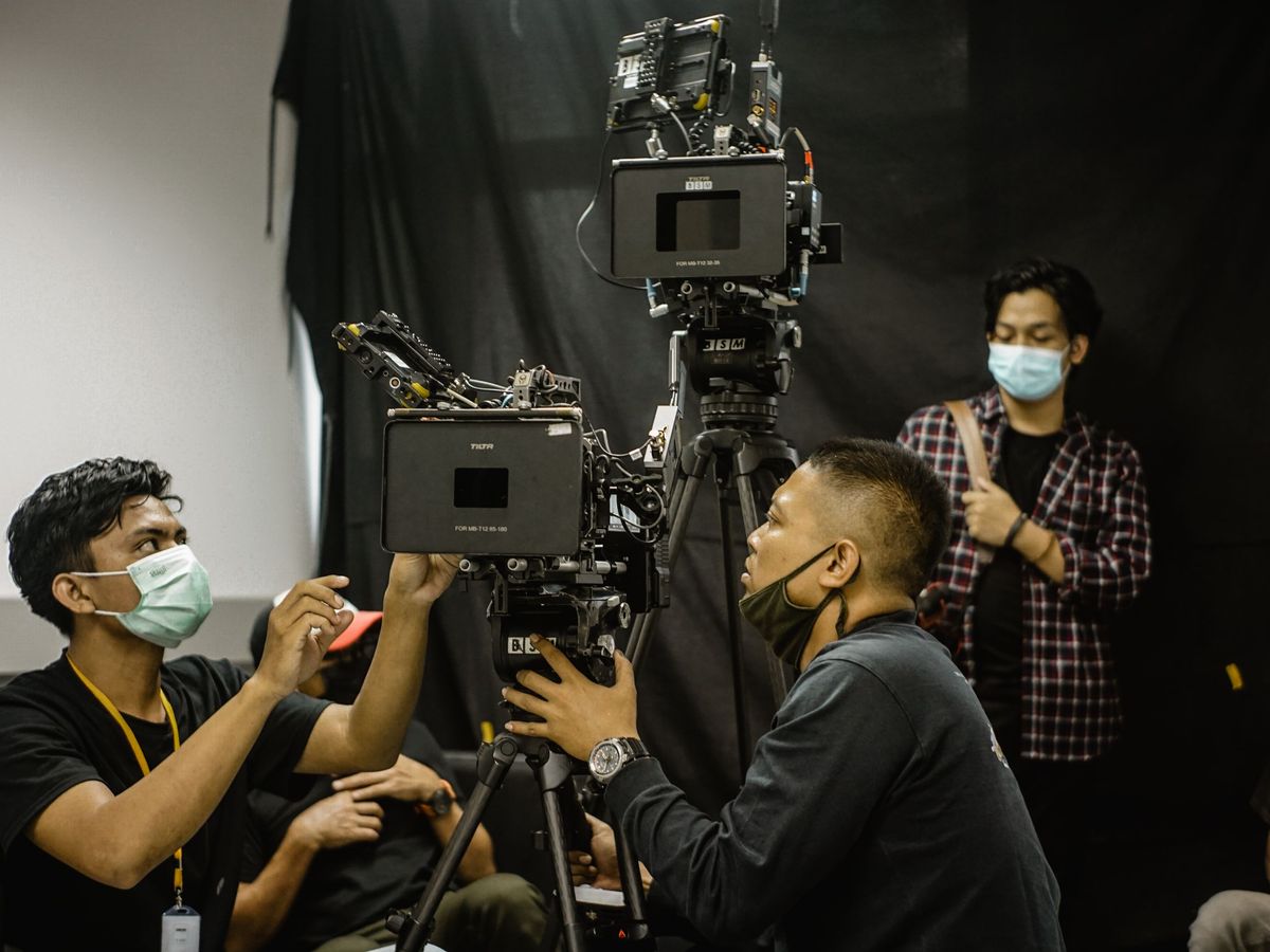 Camera crew setting up a broadcast camera on a tripod