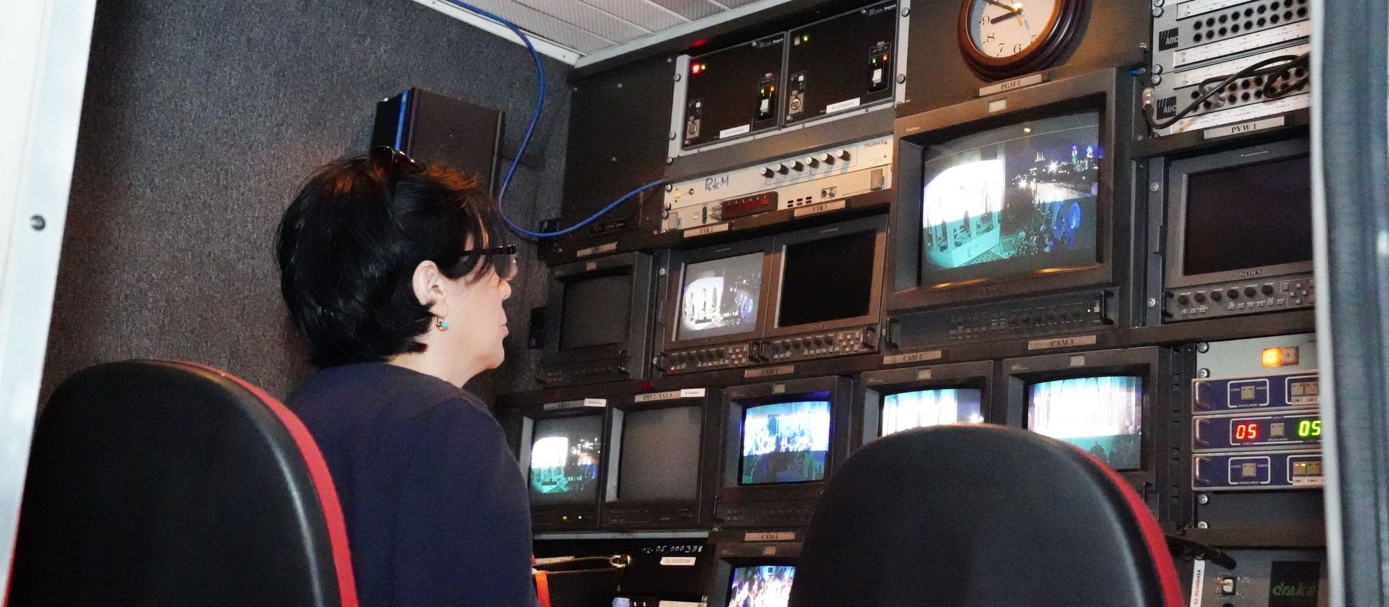 Operator in an outside broadcast control room surrounded by monitors