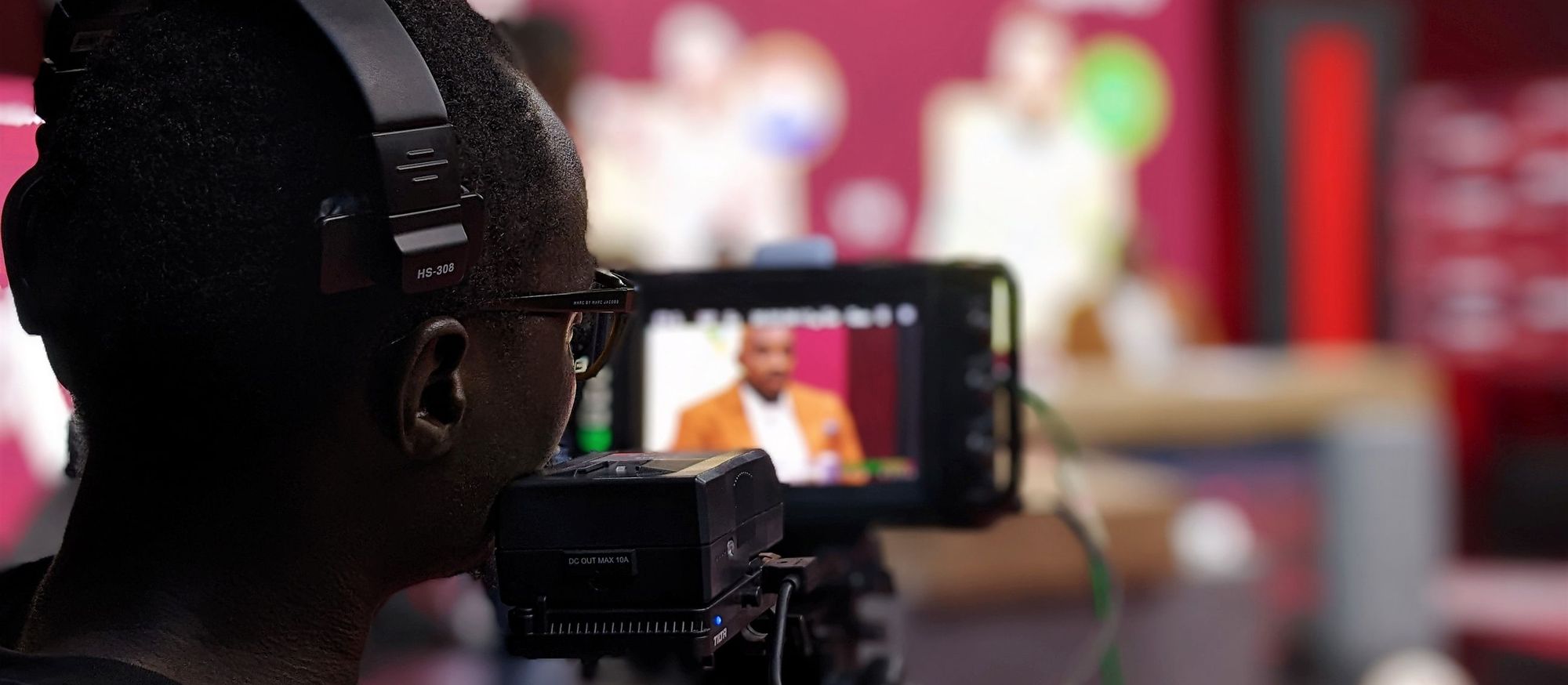 Camera operator wearing an intercom headset while filming a studio presenter