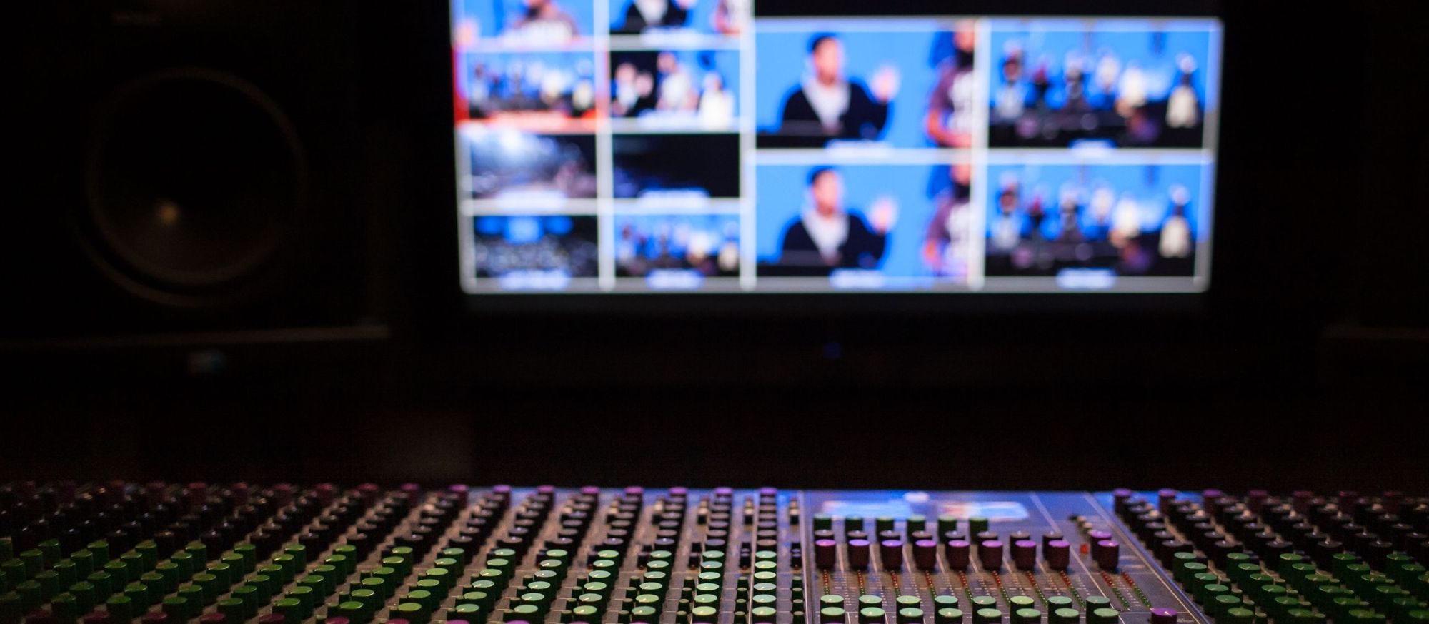 Multiviewer monitor wall above a mixing console in a broadcast control room